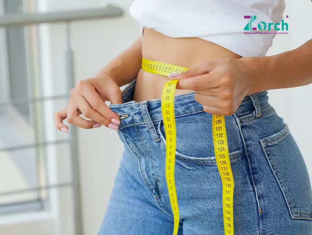 Woman measuring waist with inch tape wearing jeans – weight loss and waist reduction concept by Zorch.